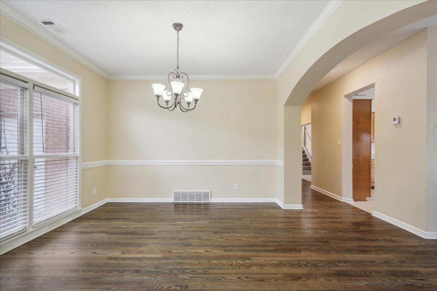8817 Dexter Road Memphis, TN 38016 - Photo 5 of 34 Spare room with a wealth of natural light, an inviting chandelier, ornamental molding, and dark hardwood / wood-style flooring