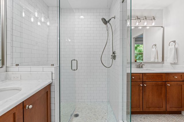 a bathroom with a granite countertop shower a sink and a mirror