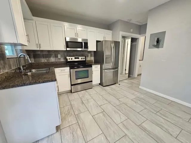 a kitchen with stainless steel appliances granite countertop a refrigerator a stove a sink and a microwave