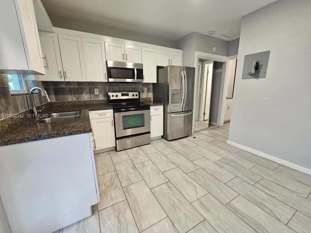 a kitchen with stainless steel appliances granite countertop a refrigerator a stove a sink and a microwave