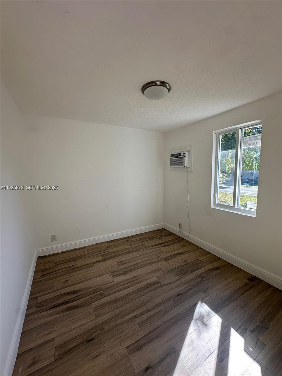 720 Southwest 7th Avenue, Unit 2 Hallandale Beach, FL 33009 - Photo 3 of 7 a view of an empty room with wooden floor and a window