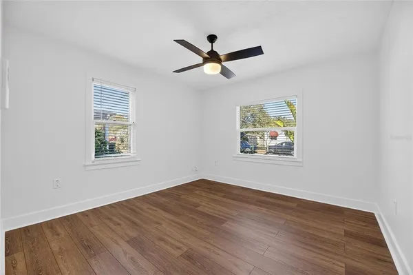 an empty room with wooden floor and windows