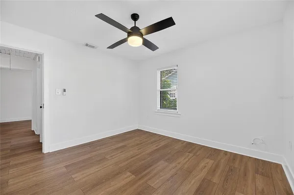 an empty room with wooden floor and ceiling fan