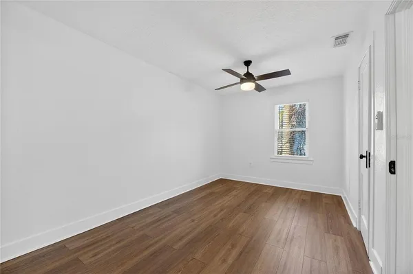 a view of empty room with wooden floor and fan