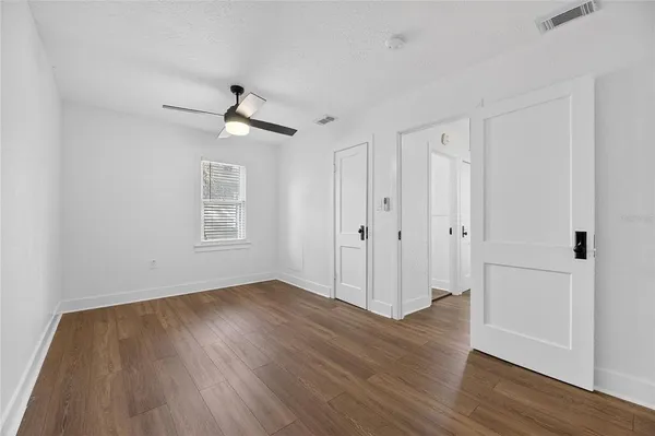 an empty room with wooden floor ceiling fan and window