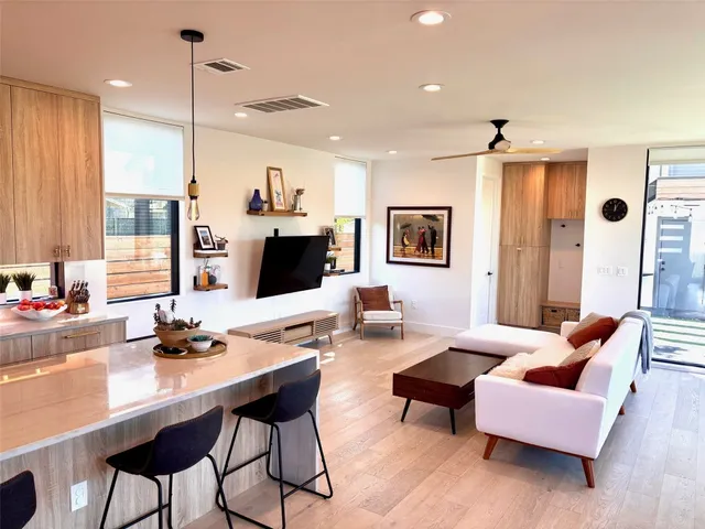 a living room with furniture kitchen view and a wooden floor