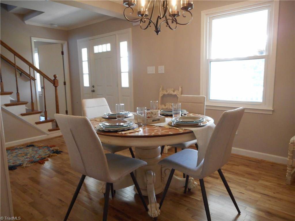 6346 Company Mill Road Climax, NC 27233 - Photo 2 of 30 In this view we are in the dining room where we can see the very nice engineered wood flooring, the window for natual lighting, the fresh new paint and the crown molding. You can also see the front entry door, the stairs to the second floor and just behind the stairs is the open door to the master bedroom and bathroom.