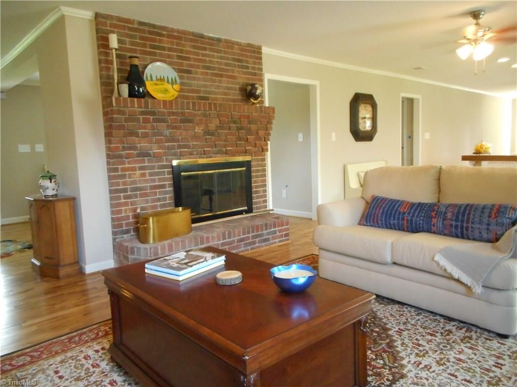 6346 Company Mill Road Climax, NC 27233 - Photo 18 of 30 In this view we are in the den looking at the wood burning fireplace. here we can also see the fresh new paint, the crown molding, and the engineered wood flooring. The hall to the left side of the fireplace is to the dining room, front entry door and the master bedroom and staircase. To the far right is the kitchen and side entry door.