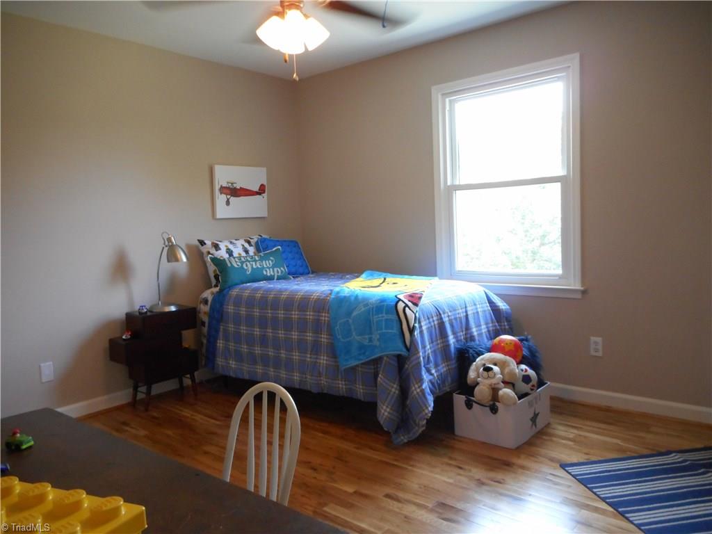 6346 Company Mill Road Climax, NC 27233 - Photo 25 of 30 In this view we are in bedroom three. Here we can see the engineered wood flooring, the window for natural lighting, the fresh new paint and the ceiling fan with light.
