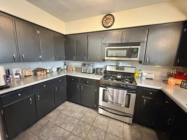 a kitchen with stainless steel appliances granite countertop a stove a sink and a microwave