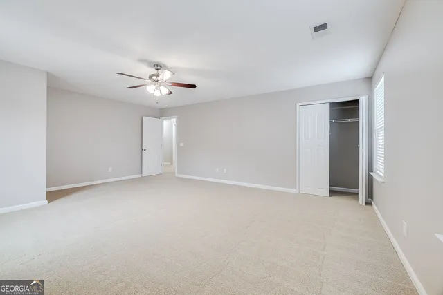 an empty room with closet and a ceiling fan