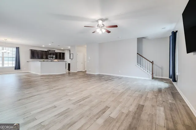 a view of a livingroom with wooden floor and ceiling fan