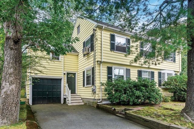 a view of a house with a small yard and large tree