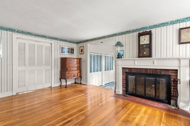 a view of an empty room with wooden floor fireplace and a window