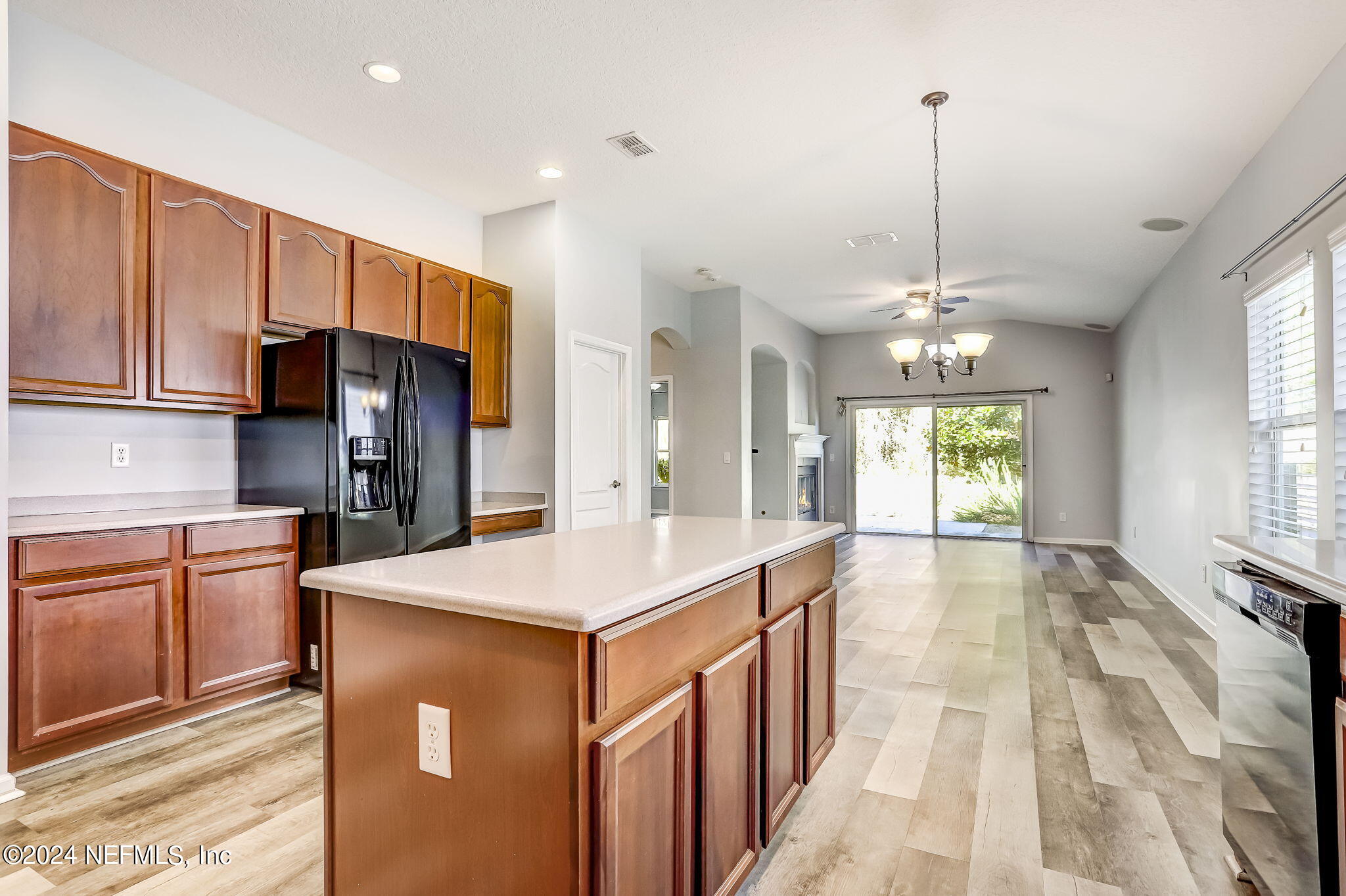 a kitchen with stainless steel appliances kitchen island granite countertop a refrigerator a sink dishwasher and white cabinets with wooden floor