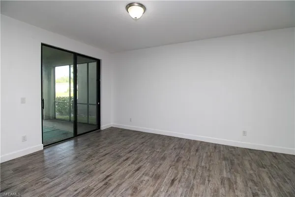an empty room with wooden floor and mirror