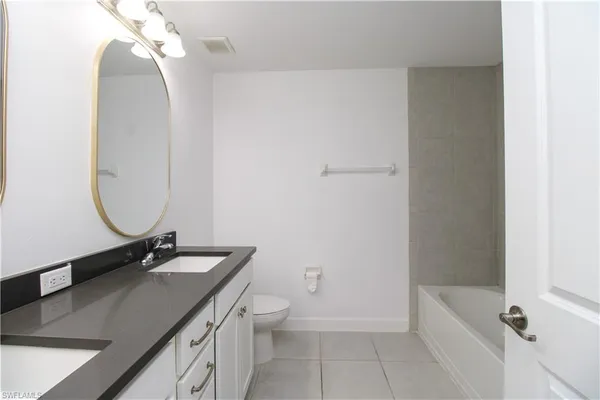 a bathroom with a granite countertop sink a toilet and bathtub