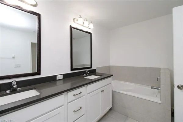 a bathroom with a granite countertop bathtub sink double and mirror