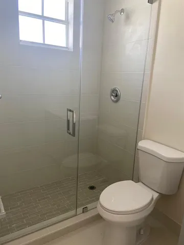 a white toilet sitting next to a shower