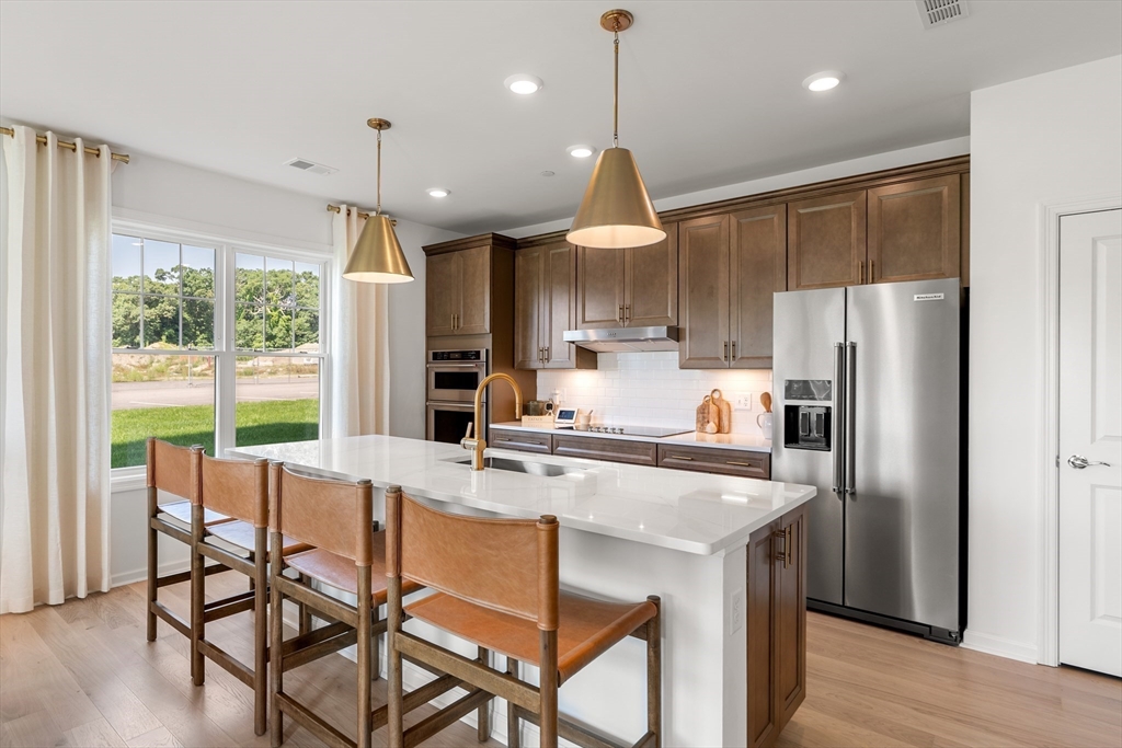 2 Codman Way, Unit 207 Westborough, MA 01581 - Photo 2 of 40 a kitchen with stainless steel appliances granite countertop a stove a refrigerator a oven a sink with a dining table and chairs
