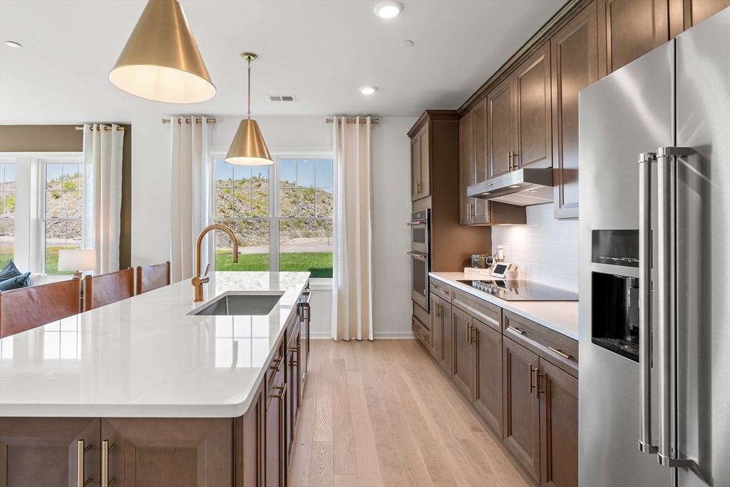 2 Codman Way, Unit 207 Westborough, MA 01581 - Photo 8 of 40 a kitchen with stainless steel appliances a stove a refrigerator a sink and a dining table with wooden floor