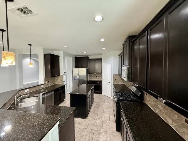a kitchen with stainless steel appliances granite countertop a sink stove and refrigerator