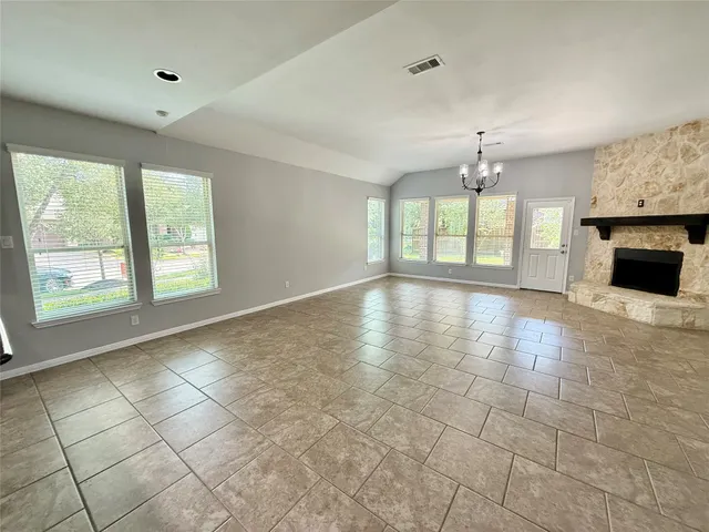 a view of an empty room with window and chandelier fan