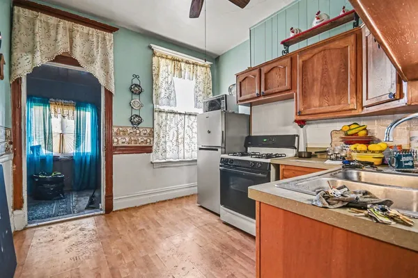 a kitchen with stainless steel appliances granite countertop a stove refrigerator and a sink with wooden floor