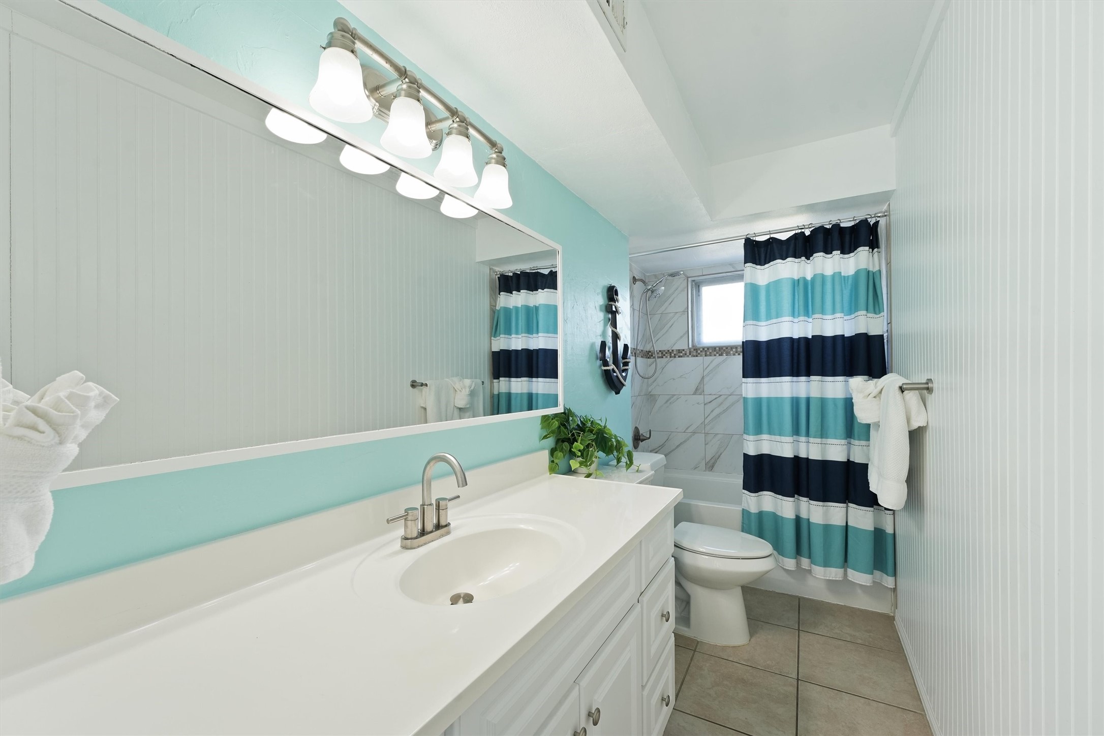 17607 Termini-San Luis Pass Road Galveston, TX 77554 - Photo 22 of 42 The primary bathroom showcases a fresh coastal palette, adding to the serene and calming ambiance. The full bath includes a combination tub and shower, highlighted by chic striped curtains and sleek vanity lighting.