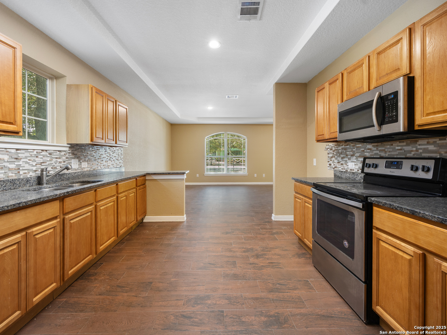 104 Viewpoint Drive Poteet, TX 78065 - Photo 8 of 23 a large kitchen with stainless steel appliances granite countertop a stove a sink dishwasher and a microwave oven with wooden floor