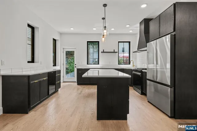 a kitchen with kitchen island granite countertop a refrigerator a sink a stove and wooden cabinets