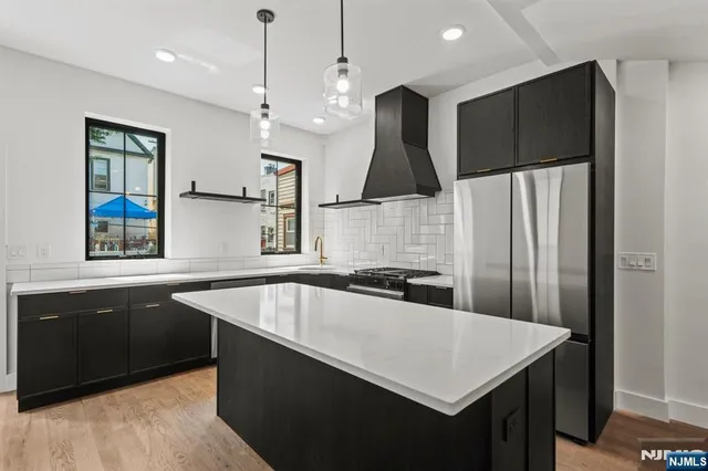 a kitchen with stainless steel appliances granite countertop a sink a stove and a refrigerator