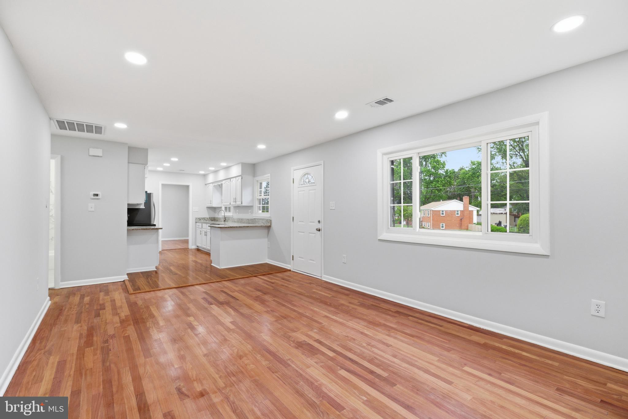 14033 Grayson Road Woodbridge, VA 22191 - Photo 6 of 33 a view of a kitchen with kitchen island a window wooden floor and a refrigerator