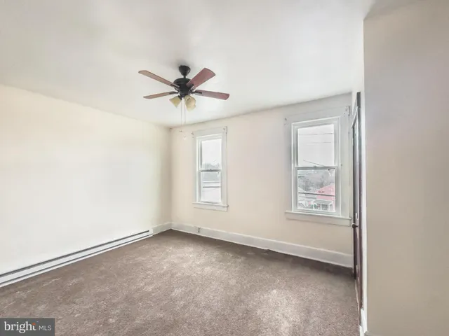 an empty room with a window and a fan