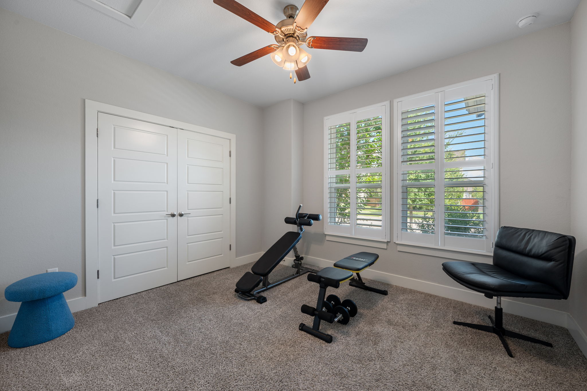 5409 Fox Wing Way Austin, TX 78747 - Photo 13 of 26 Bright windows with plantation shutters illuminate a versatile exercise room with carpeted flooring and ceiling fan.