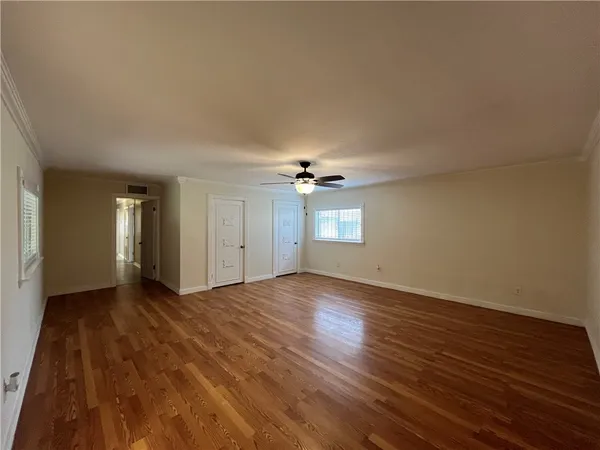 a view of empty room with wooden floor and ceiling fan