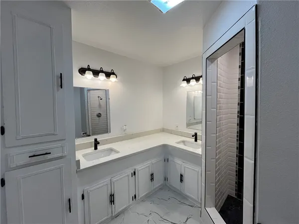 a bathroom with a double vanity sink mirror and bathtub