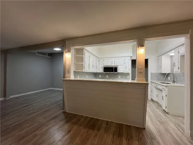 a large kitchen with cabinets wooden floor and stainless steel appliances