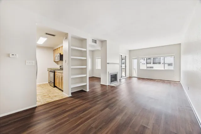a view of an empty room with a window and wooden floor
