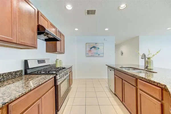 a kitchen with stainless steel appliances granite countertop a stove a sink and a microwave