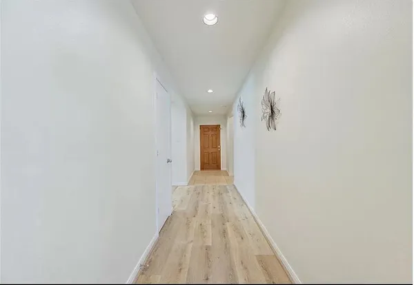 a view of a hallway with wooden floor and a bathroom