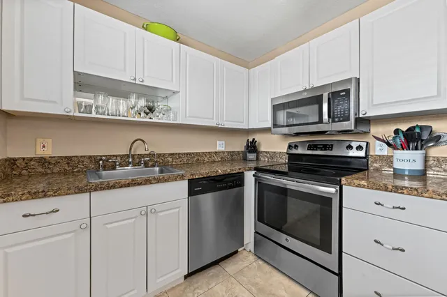 a kitchen with granite countertop white cabinets stainless steel appliances and a sink