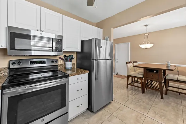 a kitchen with granite countertop a refrigerator stove and white cabinets