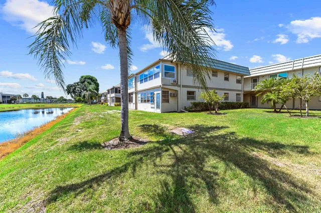 a view of a house with a big yard and palm trees