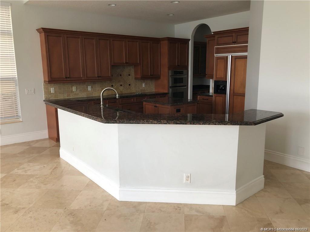 108 Tulip Tree Court Jupiter, FL 33458 - Photo 29 of 41 a kitchen with granite countertop a sink and a stove with wooden cabinets
