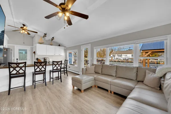 a living room with furniture kitchen view and a wooden floor