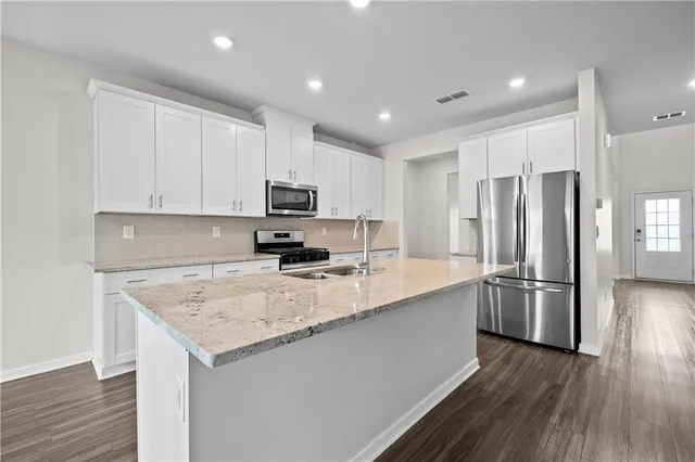 a kitchen with kitchen island granite countertop stainless steel appliances and wooden cabinets