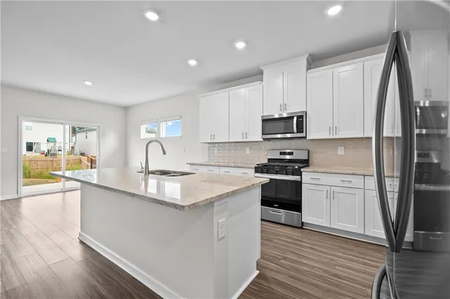 a kitchen with stainless steel appliances granite countertop a stove a sink and a refrigerator