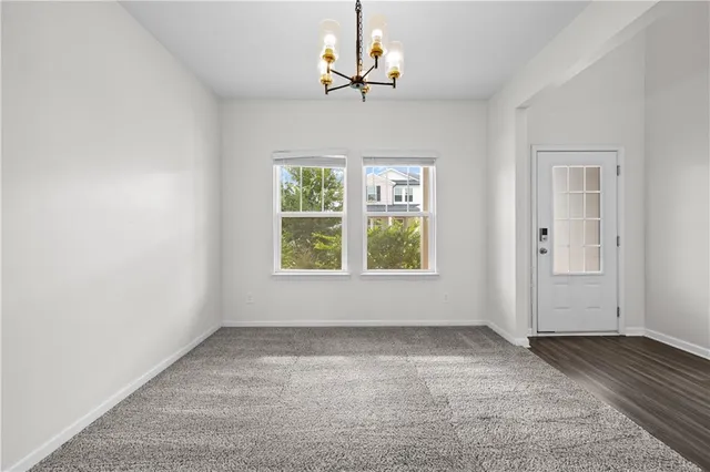 an empty room with wooden floor chandelier and windows