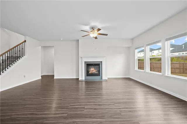 an empty room with wooden floor chandelier fan and windows